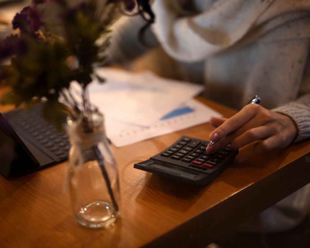 Close-up of a person using a calculator while reviewing financial documents.