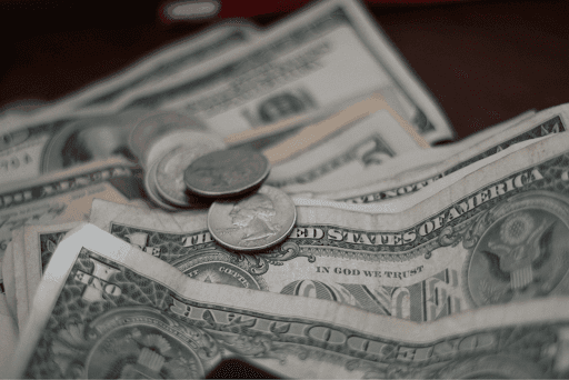 Close-up of scattered U.S. dollar bills and coins on a surface.