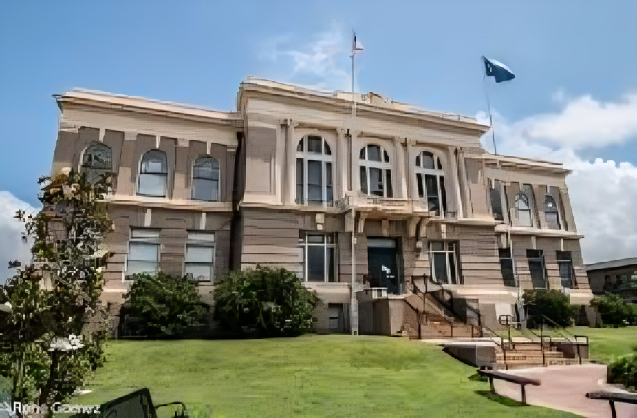 Historic courthouse with a neoclassical architectural style, a grand staircase, and surrounding greenery.