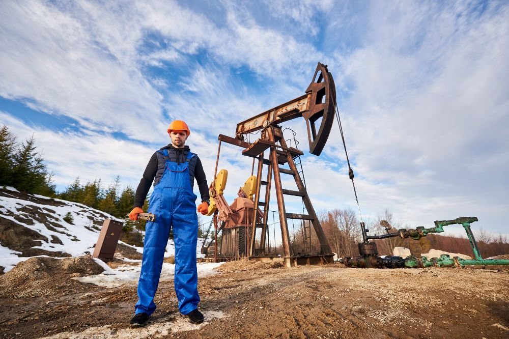 A tall oil drilling rig standing in a grassy field under a clear sky.