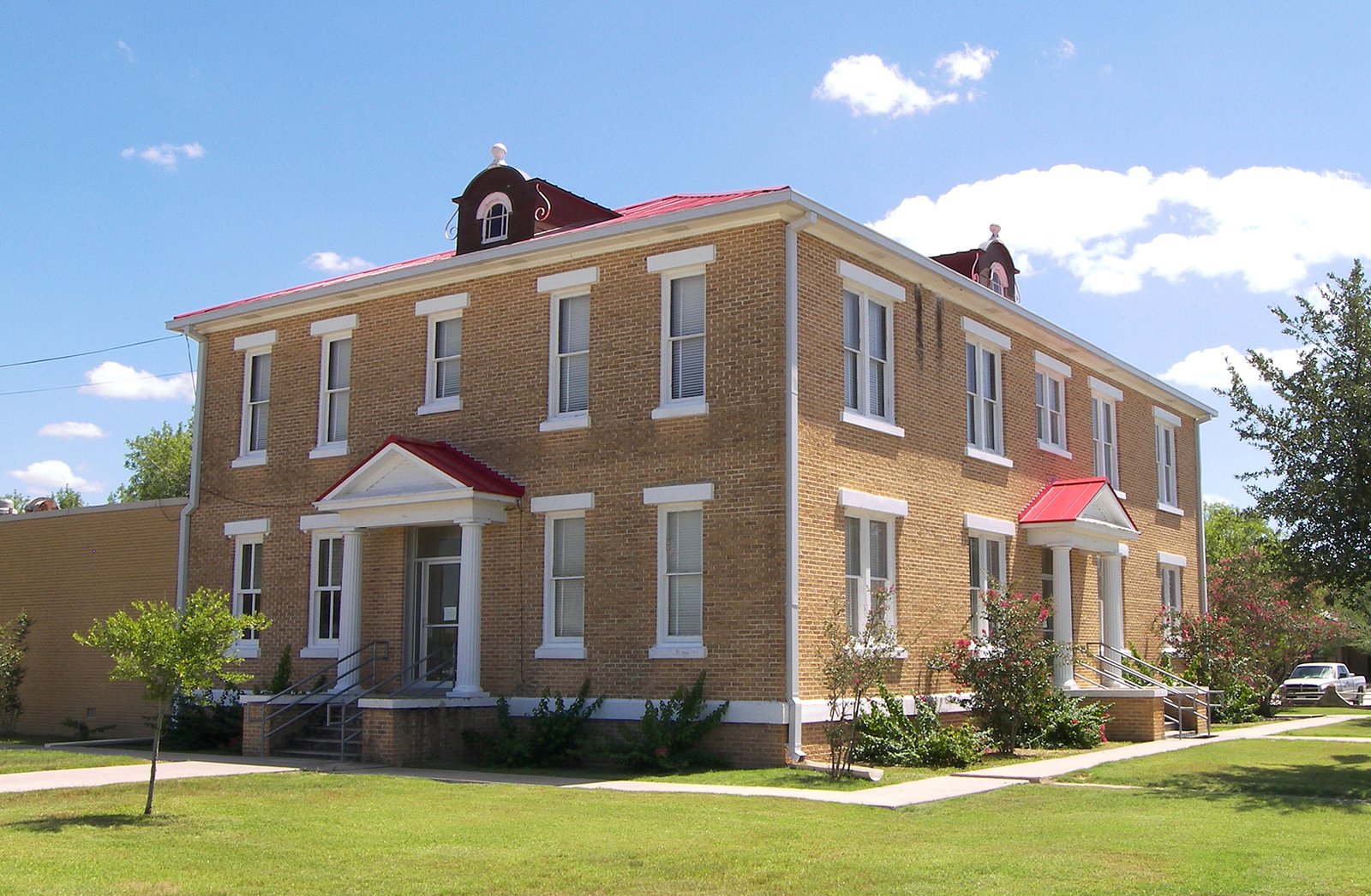 McMullen County Courthouse, a historic two-story brick building with red roofs and colonial-style columns
