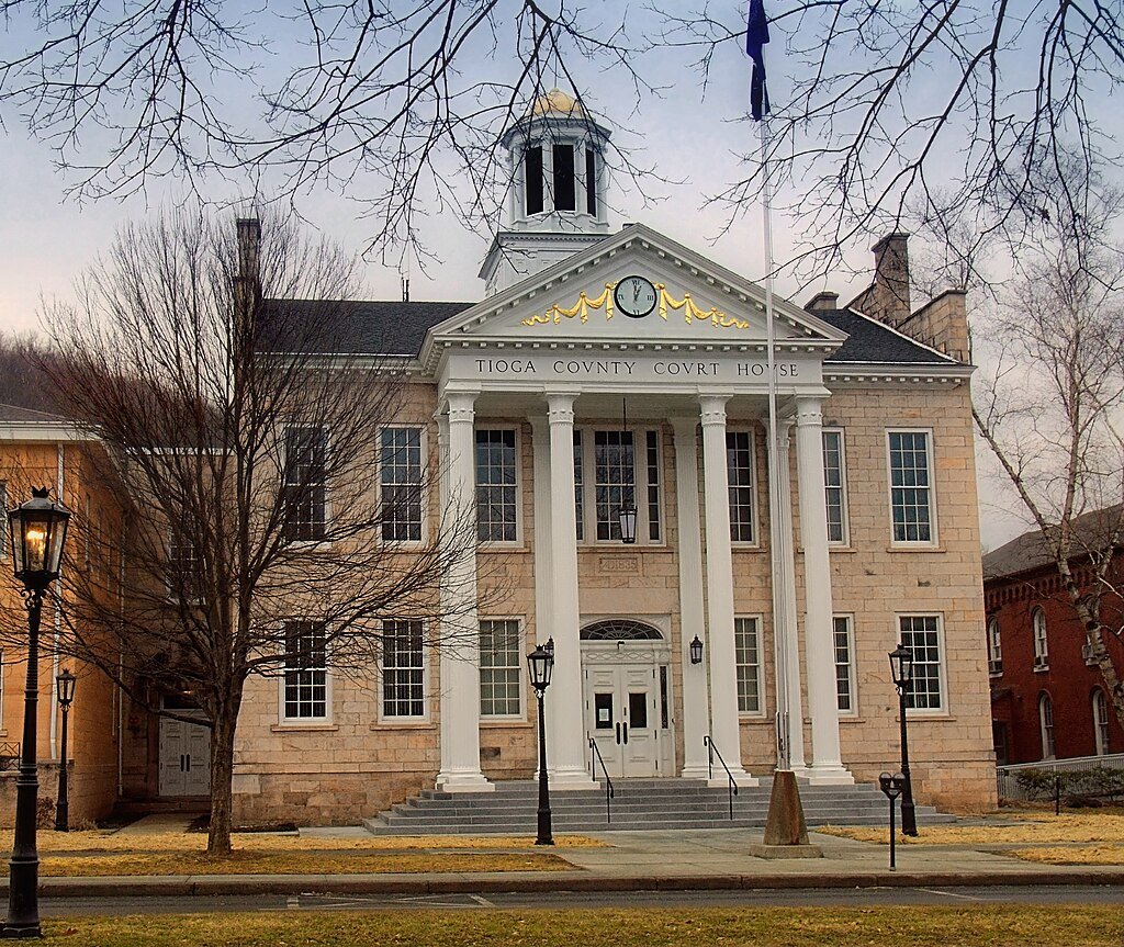 Tioga County Courthouse with white columns, golden accents, and a historic neoclassical facade.