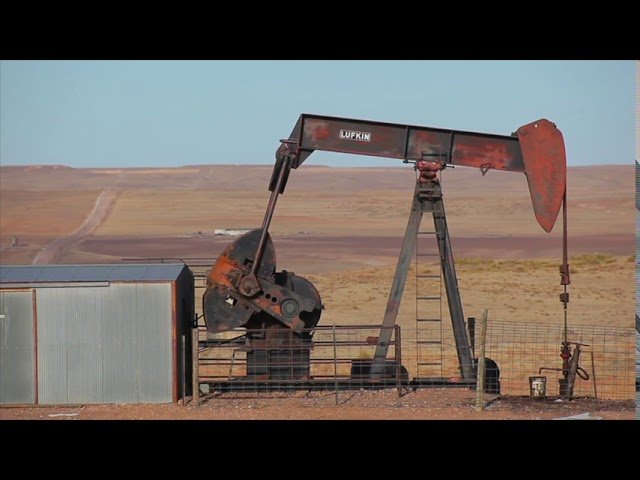 Rustic Lufkin oil pumpjack operating in a remote desert landscape, symbolizing traditional oil extraction.